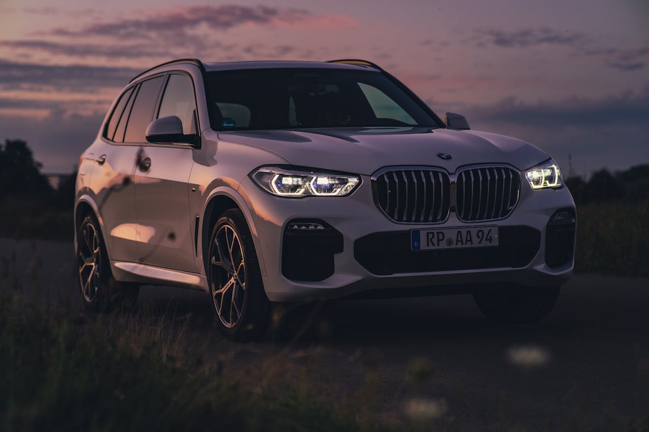 A sleek white BMW SUV parked in a serene outdoor landscape during twilight.